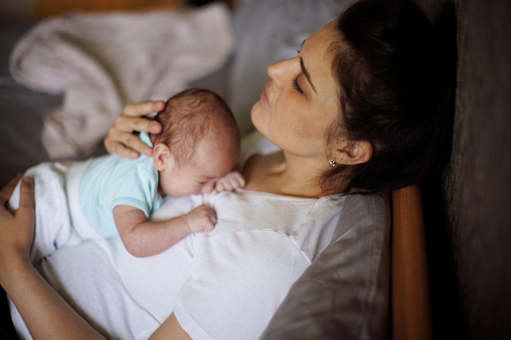 Exhausted mother holding her crying newborn baby. Postpartum depression.